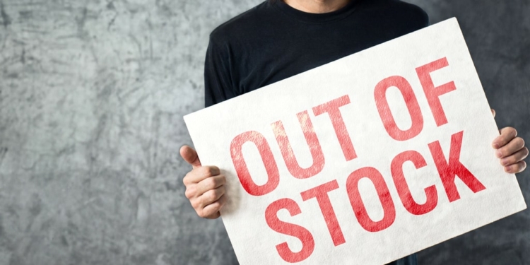 Out of Stock sign in hands of storage employee, shortage in supply chain