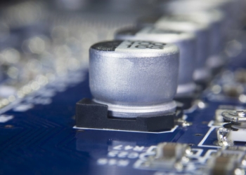 Close up macro of aluminum electrolytic capacitors installed on the motherboard and electronic component with selective focus. Electronics part concept.