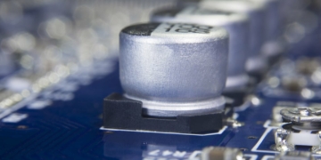 Close up macro of aluminum electrolytic capacitors installed on the motherboard and electronic component with selective focus. Electronics part concept.