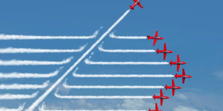 Game changer business or political change concept and disruptive innovation symbol and be an independent thinker with new industry ideas as an individual jet breaking through a group of airplane smoke as a metaphor for defiant leadership.