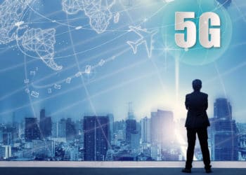 5G network wireless systems and internet of things with successful businessman standing on top of building and looking through Cityscape Skyline Night Light, Connect global wireless devices.