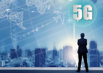 5G network wireless systems and internet of things with successful businessman standing on top of building and looking through Cityscape Skyline Night Light, Connect global wireless devices.