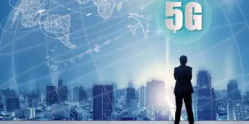 5G network wireless systems and internet of things with successful businessman standing on top of building and looking through Cityscape Skyline Night Light, Connect global wireless devices.