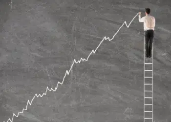 Young businessman on a ladder charting a positive trend graph