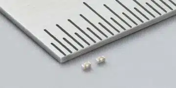 Two Murata LLD three-terminal MLCCs beside a metal ruler, showing beige ceramic bodies and silver-coloured terminals.